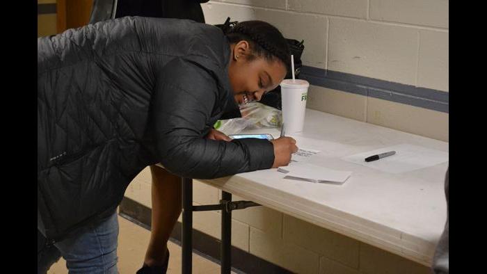 Brianna Johnson, an 11th grader at Lincoln Park High School, writes down her questions ahead of the forum.