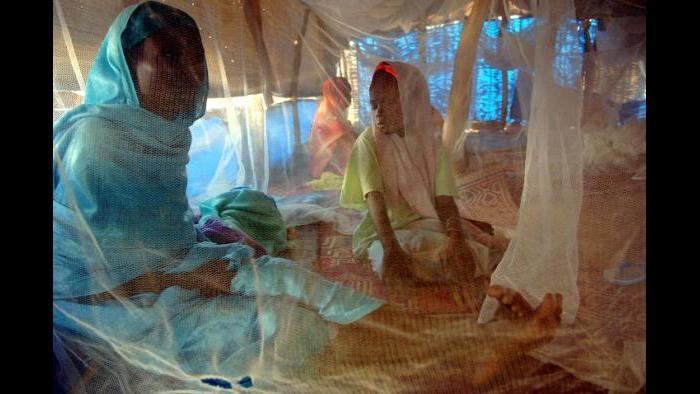 An Internally displaced mother and daughter sit beneath a mosquito net while being treated for malnutriti​on in Nyala, South Darfur, Sudan, November 2005. (Lynsey Addario)