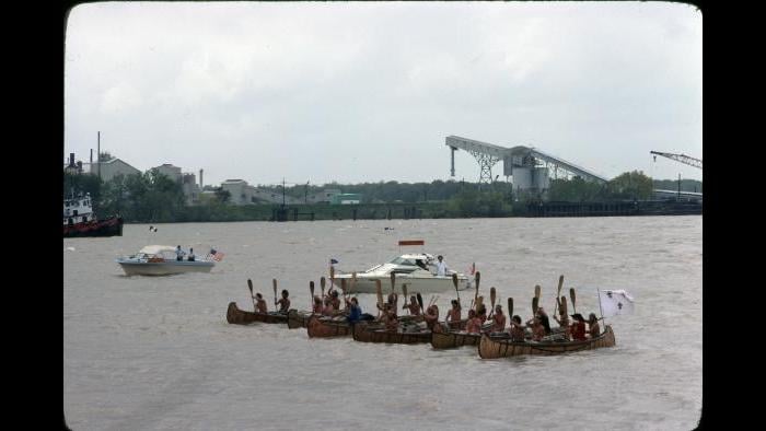 All six canoes stop for a paddle salute outside New Orleans on April 3, 1977, while a crowd and a fleet of powerboats look on. (Photographers of the La Salle: Expedition II)