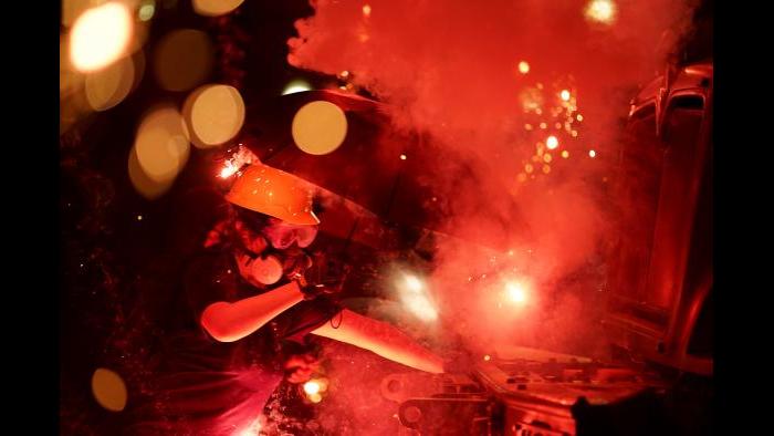 An explosive device detonates as a protester pushes back on an armored vehicle clearing the park of demonstrators during clashes outside the Kenosha County Courthouse, late Tuesday, Aug. 25, 2020, in Kenosha, Wis. Protests continue following the police shooting of Jacob Blake two days earlier. (AP Photo/David Goldman)