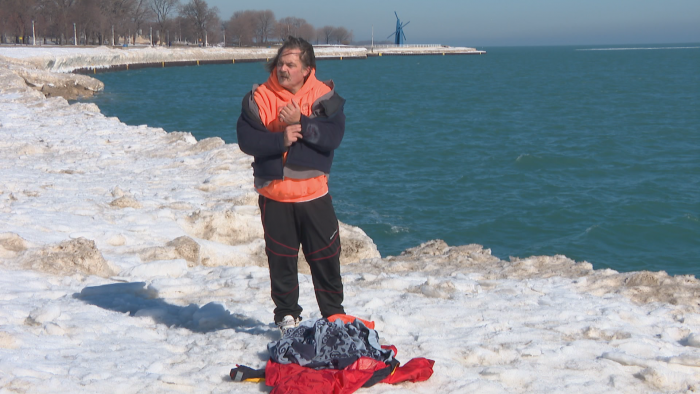 Dan O’Conor strips off his outer layer of clothing at Fullerton Beach before plunging into Lake Michigan on Feb. 26, 2021. (WTTW News)