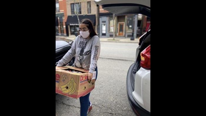 A volunteer carries a box of bananas that will be distributed to families in need through the Feed the Crib initiative. (Courtesy Elizabeth Morales)