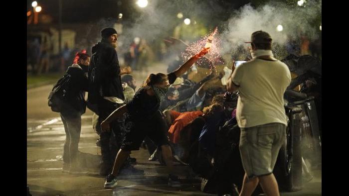 A protester tosses an object toward police during clashes outside the Kenosha County Courthouse late Tuesday, Aug. 25, 2020, in Kenosha, Wis. (AP Photo / David Goldman)
