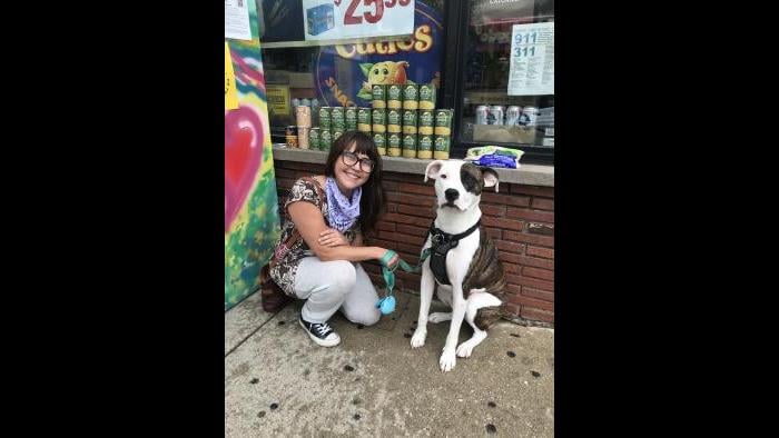 Allie Mae Miller and her dog, Abe, sit next to the refrigerator she painted and donated to the Love Fridge project in Avondale. (Ariel Parrella-Aureli / WTTW News)