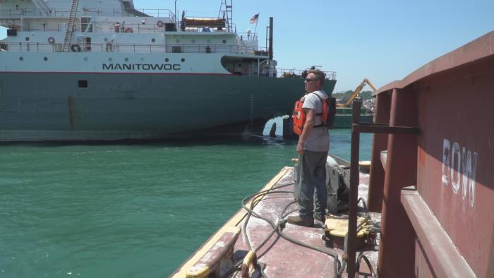 Deckhand Bill Hruska, at the front of the barge, giving signals to Captain Van Dusen.  