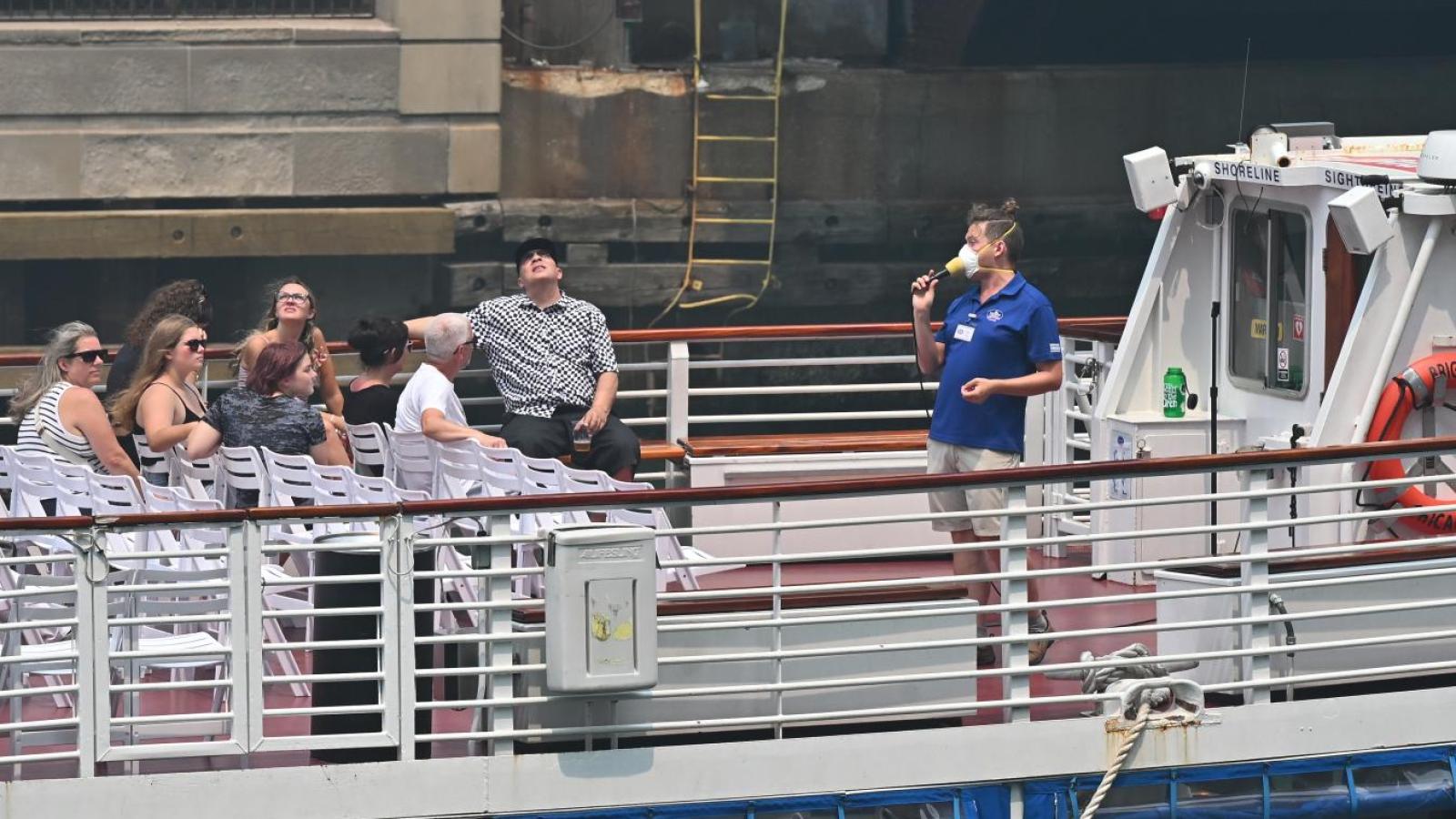 A tour boat guide on the Chicago River opts for a mask amid a hazardous air quality alert due to northern wildfires on July 16, 2026. (Victor Hilitski / WTTW News)