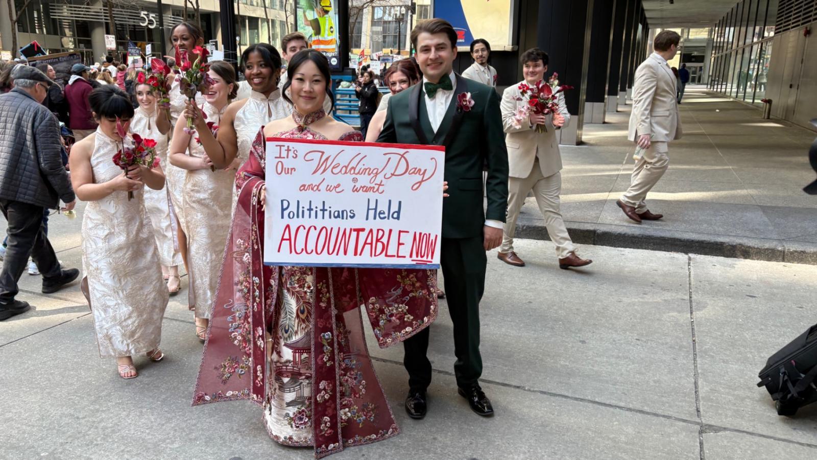 Newlyweds Sarah and Matt Bruns hold a sign during the “No Kings” protest on March 28, 2026. (Joel Ortiz / WTTW News)
