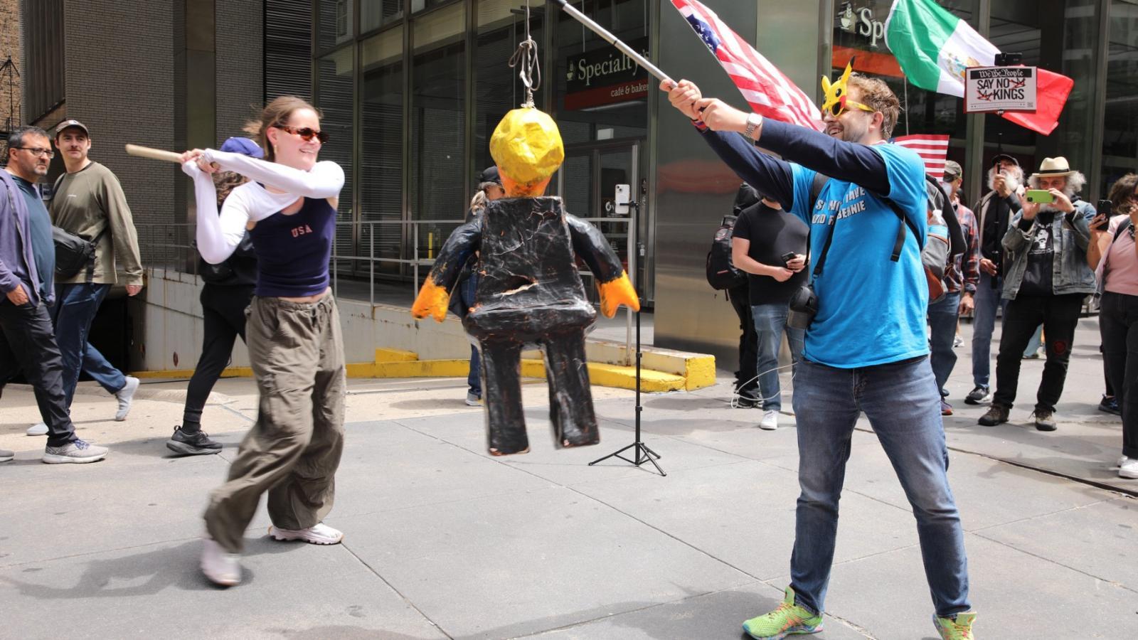 Protesters at Daley Plaza take a break to take a swing at a Donald Trump piñata on Saturday, June 14, 2025. (Michael Izquierdo / WTTW News)
