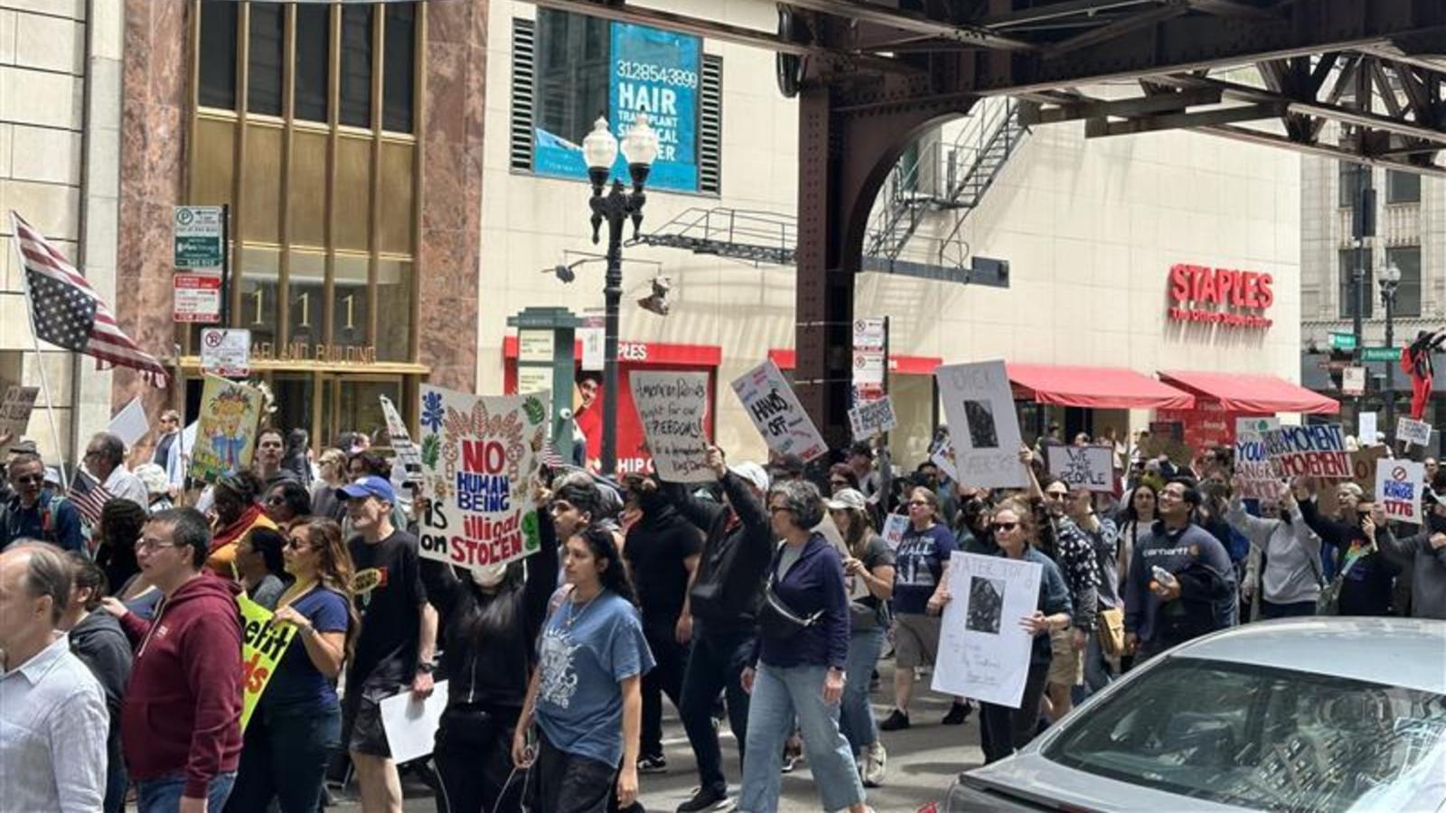 Protesters march down Monroe Street as shoppers look on. The crowd chants “No hate, no fear! Immigrants are welcome here.” (Abena Bediako / WTTW News)