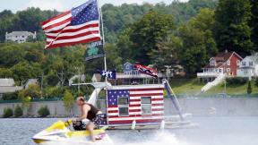 A jet skier passes a patriotic shanty-boat owned by AJ Crea on Pontoosuc Lake on Labor Day in Pittsfield, Mass., Monday, Sept. 7, 2020. (Ben Garver / The Berkshire Eagle via AP) A jet skier passes a patriotic shanty-boat owned by AJ Crea on Pontoosuc Lake on Labor Day in Pittsfield, Mass., Monday, Sept. 7, 2020. (Ben Garver / The Berkshire Eagle via AP)