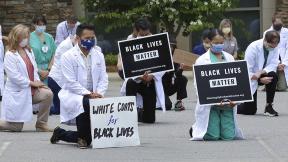 In this June 5, 2020 photo provided by the Mountain Area Health Education Center, physicians, residents and staff from the facility in Asheville, N.C., take a knee to show support for renewed calls for racial justice after the police killing of George Floyd. (Brenda Benik / MAHEC via AP) In this June 5, 2020 photo provided by the Mountain Area Health Education Center, physicians, residents and staff from the facility in Asheville, N.C., take a knee to show support for renewed calls for racial justice after the police killing of George Floyd. (Brenda Benik / MAHEC via AP)